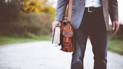 A man walks with a Bible and a briefcase